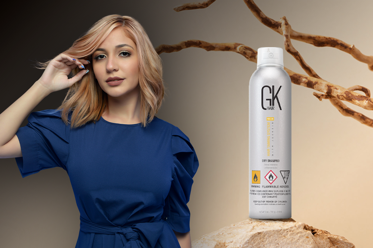 Woman spraying dry shampoo onto her roots to absorb oil between washes