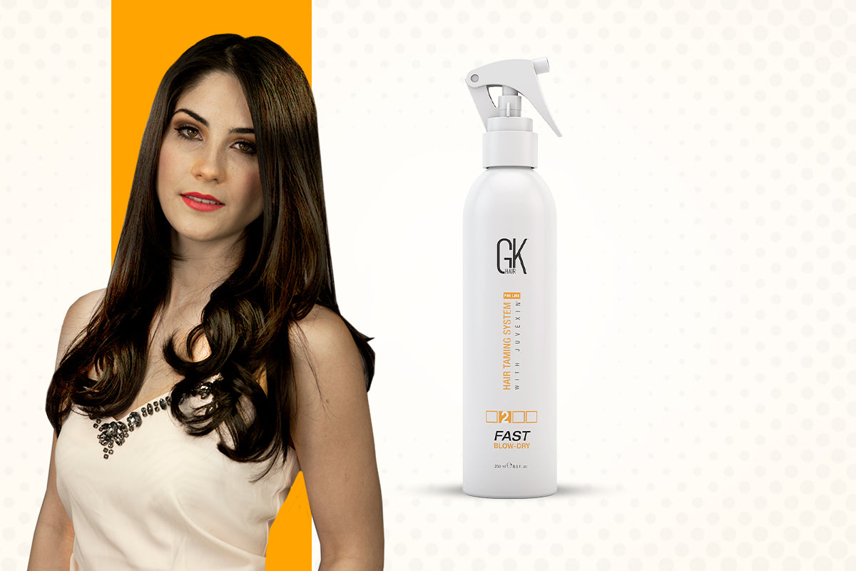 Woman with long dark wavy hair beside a white GK Hair Fast Blow-Dry spray bottle