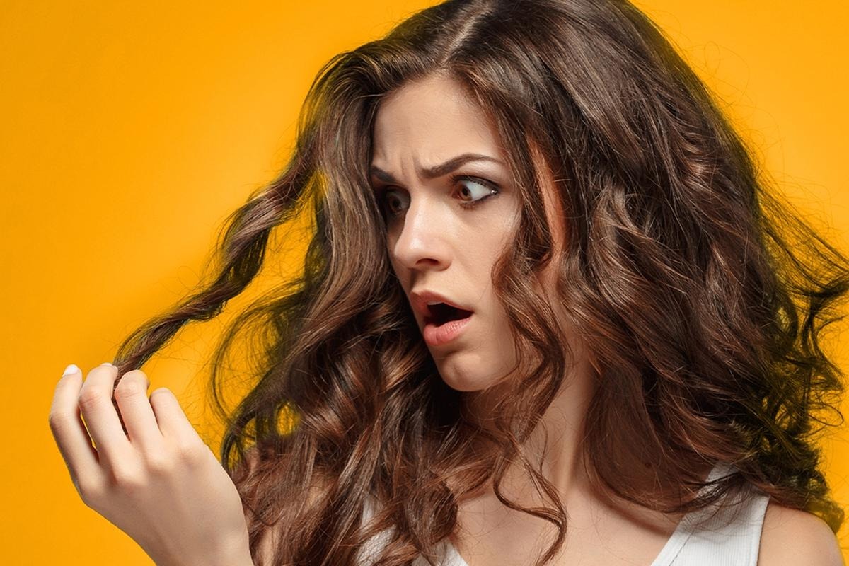 Woman brushing tangled dry hair, illustrating daily habits that damage hair strands