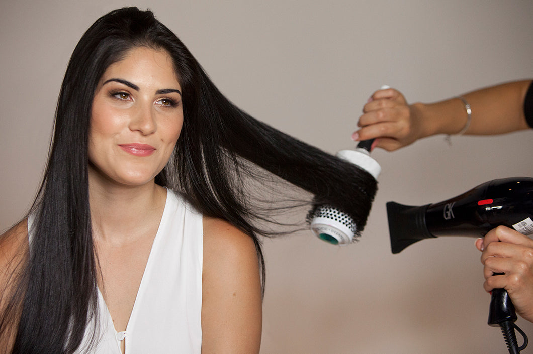 Woman blow drying her hair with a round brush and a handheld dryer