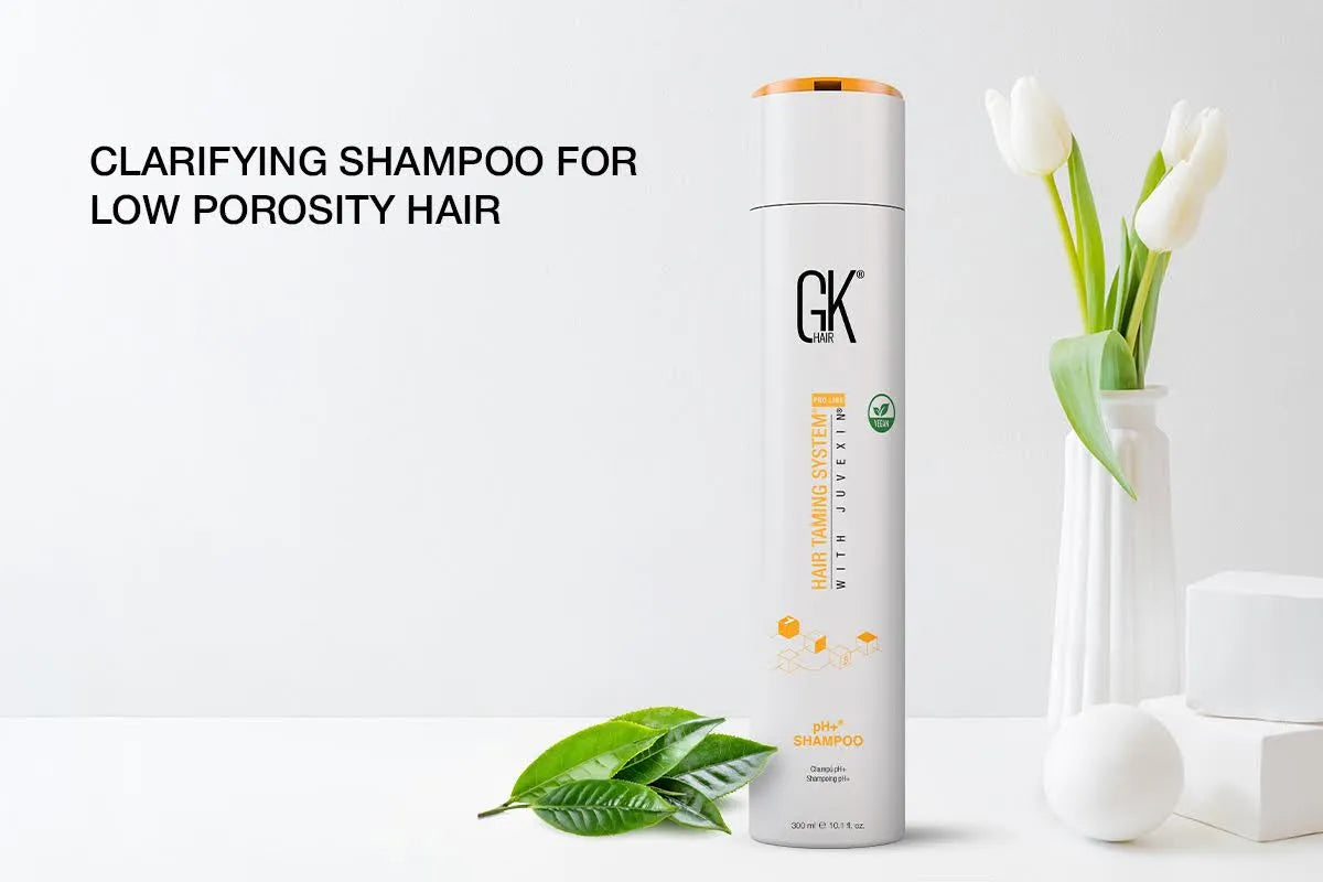 GK Hair pH+ Shampoo next to green leaves and white tulips in a vase. Text reads "Clarifying Shampoo for Low Porosity Hair."