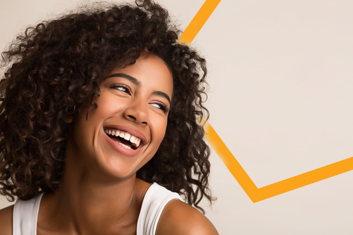 Woman laughing over her shoulder with a dark brown curly afro and white tank top, orange chevron line behind her