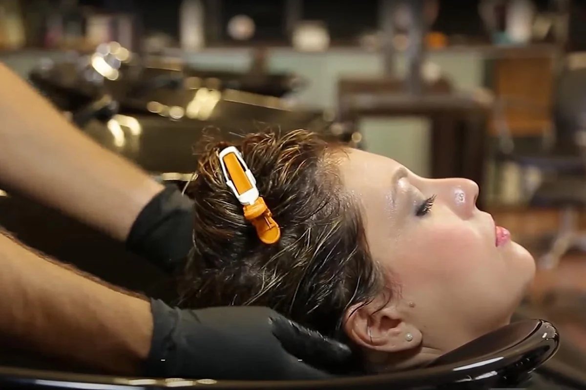 A lady washing her hair with a clarifying shampoo