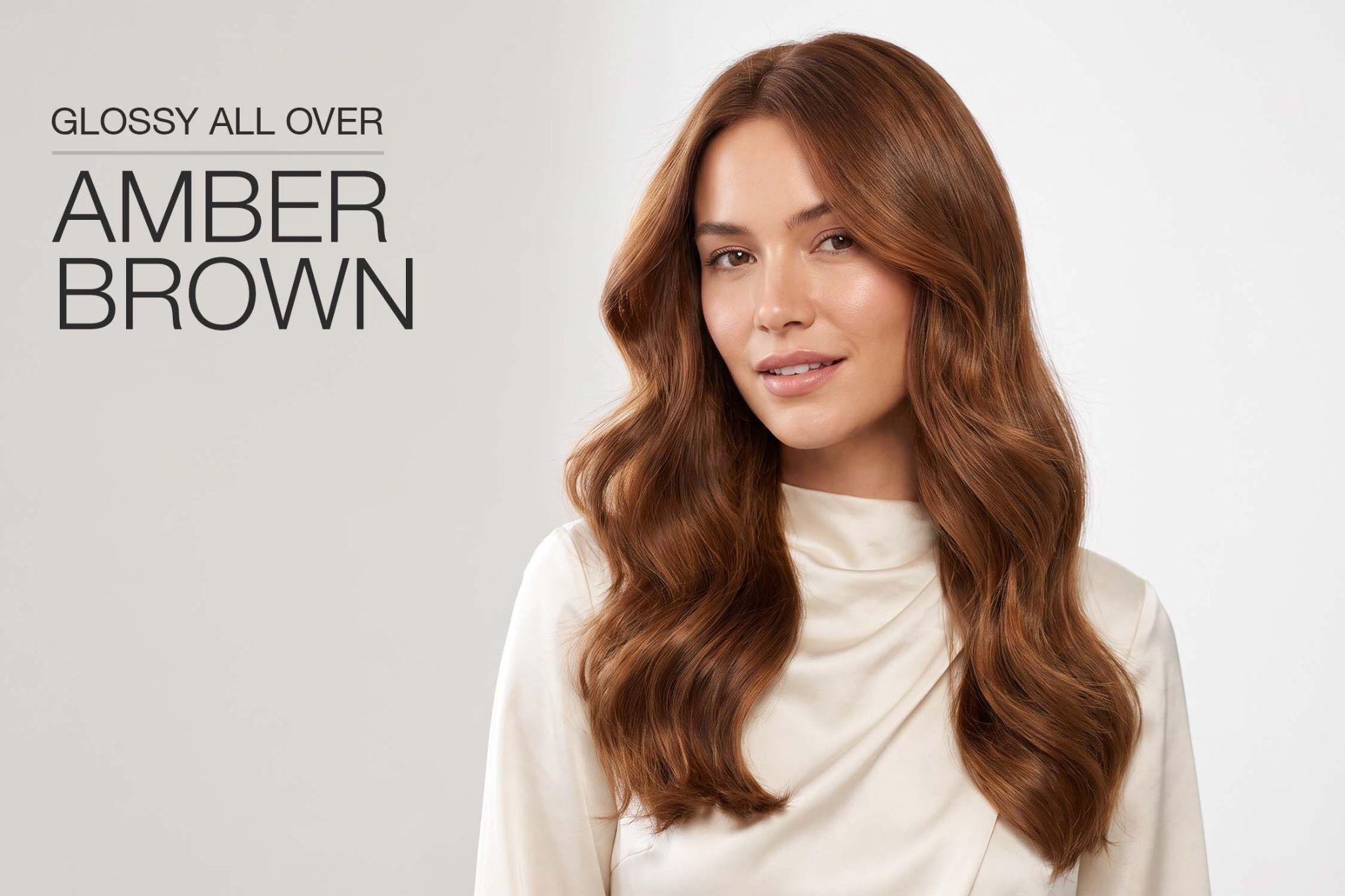 Amber hair color: woman with long, glossy amber brown waves and a cream satin top