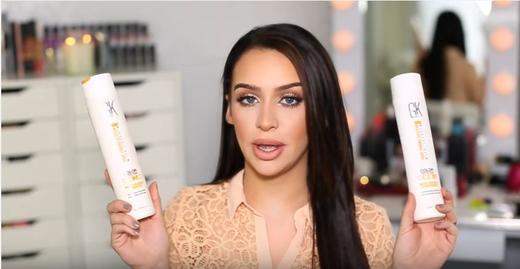 Carli Bybel holding GK Hair Moisturizing Shampoo and Conditioner bottles during a product review