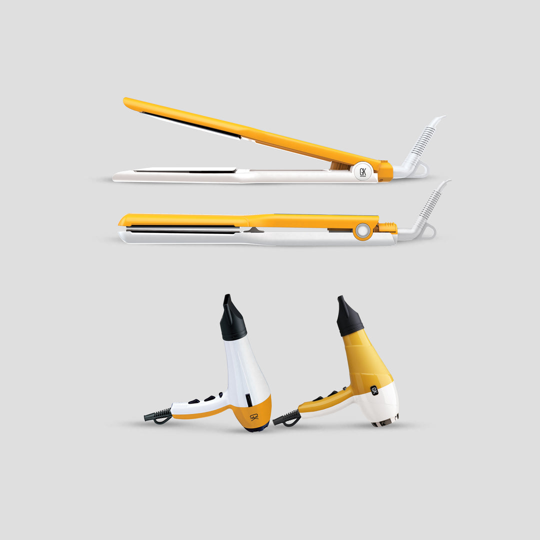 Two yellow and white GK Hair flat irons above two GK Hair blow dryers on a light gray background
