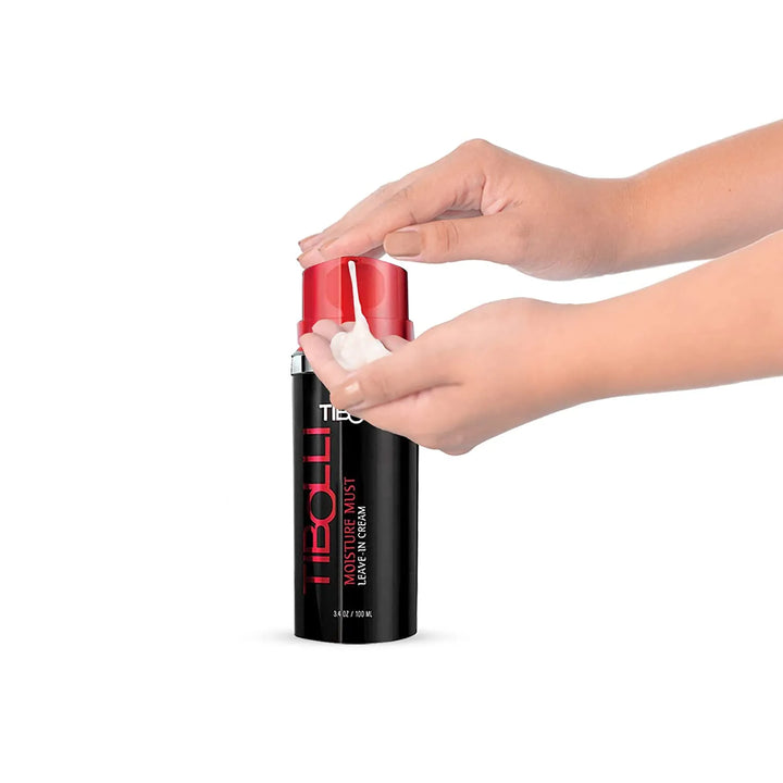 Hands dispensing white cream from a black Tibolli Moisture Must Leave-In Cream bottle with a red pump cap, 100 ml / 3.4 oz