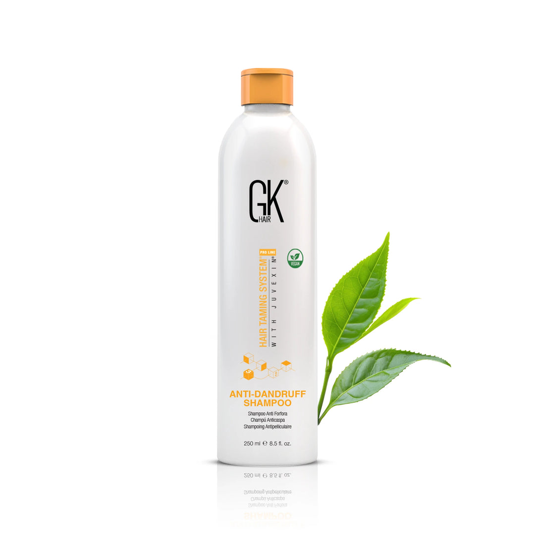 GK Hair Anti-Dandruff Shampoo 250 ml / 8.5 fl. oz. bottle with an orange cap, green tea leaves at its side on white