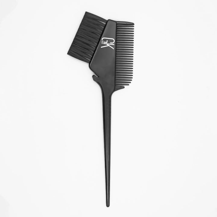 Black GK Hair application brush with soft bristles, comb teeth alongside and a long pointed tail handle, on white