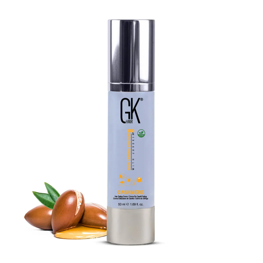 GK Hair Cashmere Hair Styling Cream 50 ml pale blue pump bottle with a silver cap beside argan nuts and oil on white