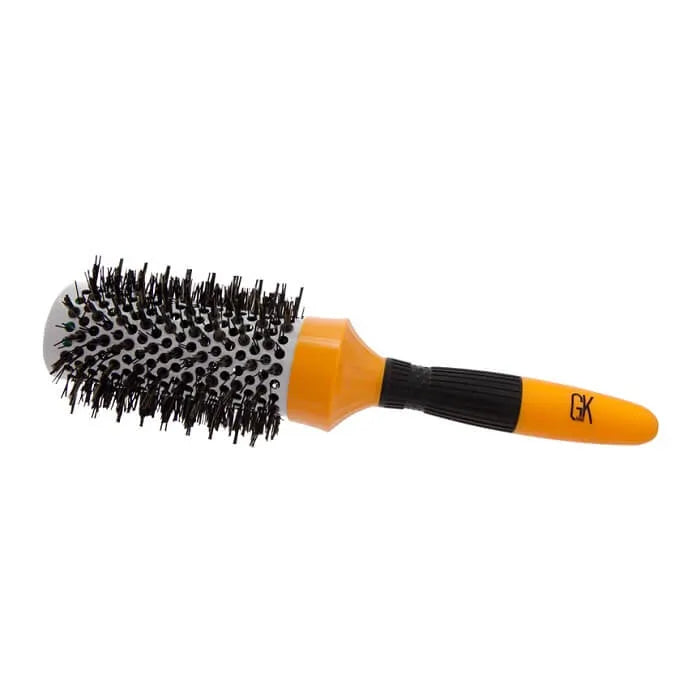 GK Hair Extra Round Hair Brush Pro lying on its side, showing the orange barrel, dense black bristles and ribbed grip, on white