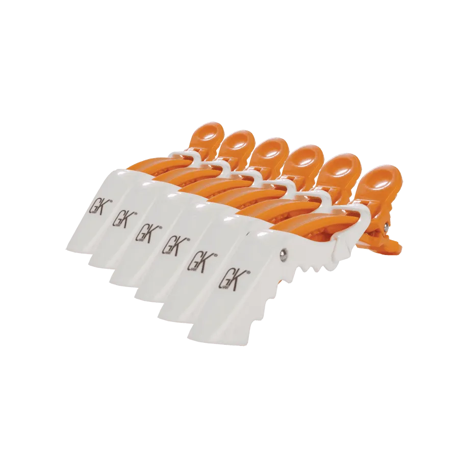Set of six GK Hair sectioning clips with white GK-logo jaws and orange grips, fanned in a row on a white background