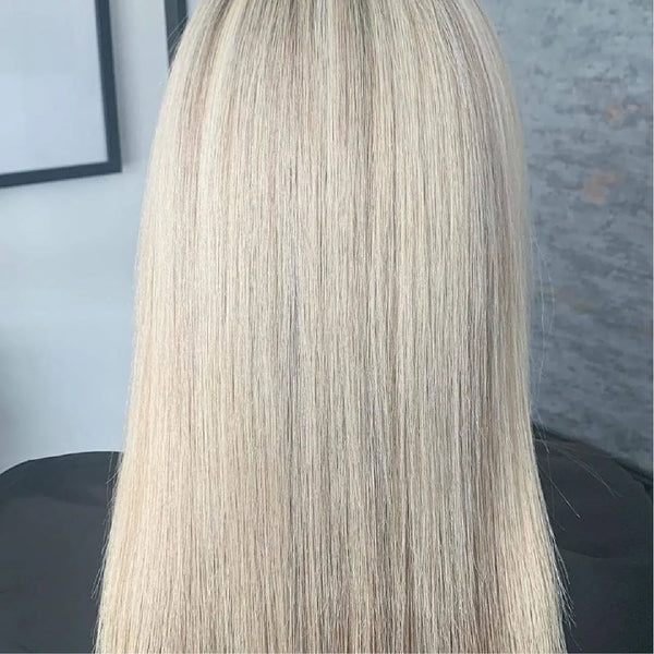 Back view of long, sleek platinum blonde hair with shadowed roots, framed picture and salon wall behind