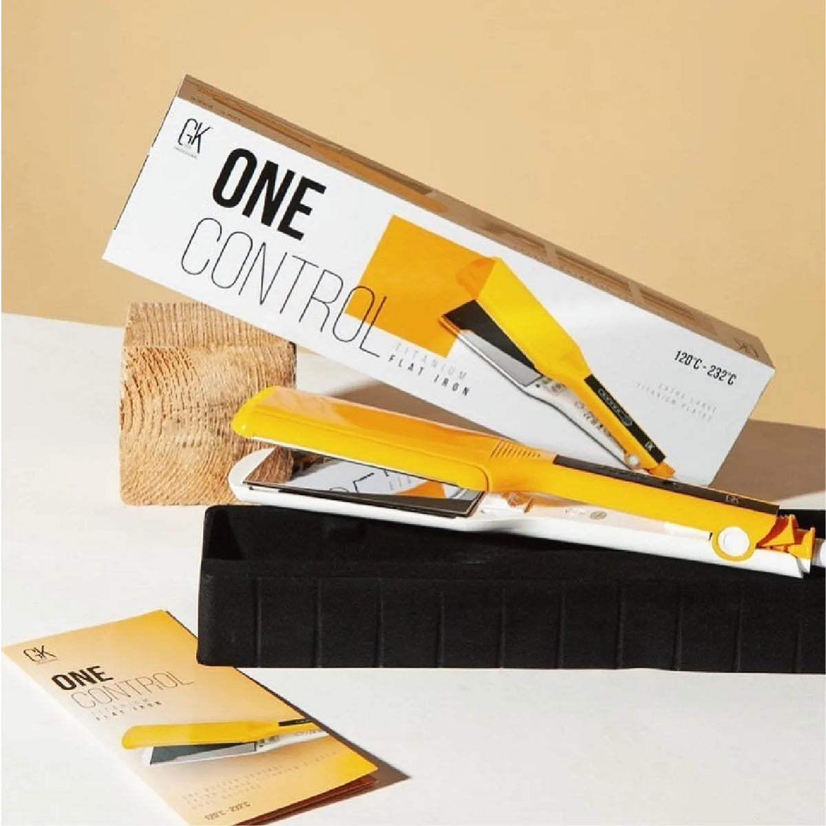 GK Hair ONE CONTROL Titanium Flat Iron in yellow leaning on its white box, which prints 120°C - 232°C, on a beige backdrop