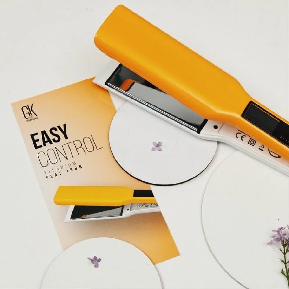 GK Hair EASY CONTROL Titanium Flat Iron in yellow lying across its card with white circles and small purple flowers