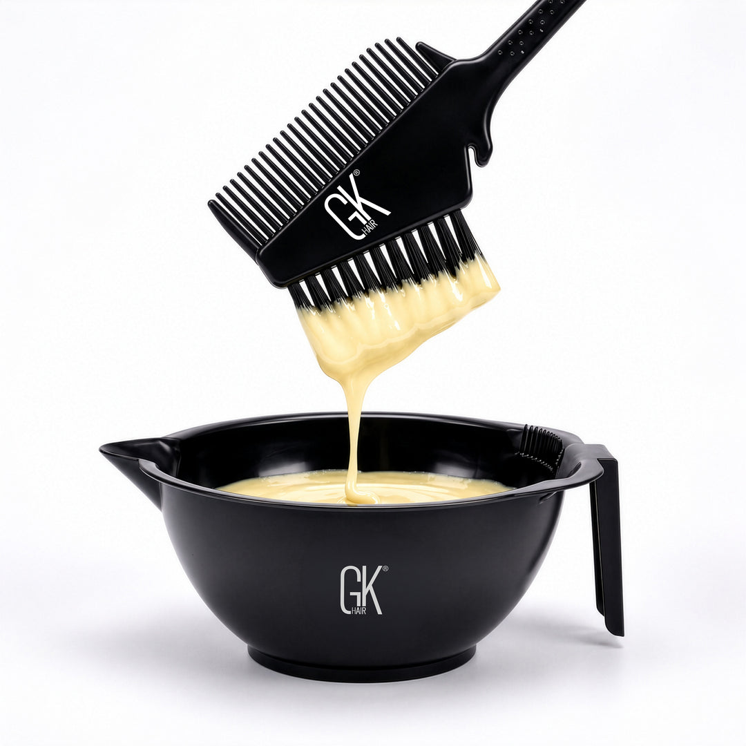 Black GK Hair brush-and-comb lifting pale yellow lightener from a black GK Hair mixing bowl, on white