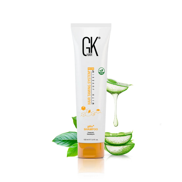 GK Hair pH+ Shampoo 100 ml white tube with an orange cap and vegan badge, beside sliced aloe vera and green leaves