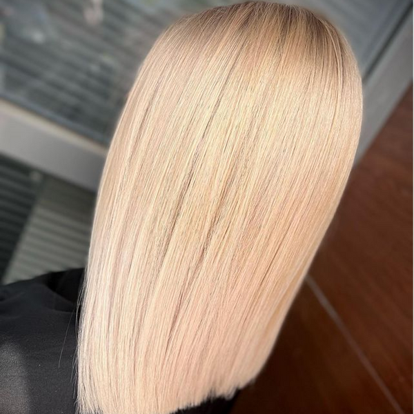 Overhead back view of sleek straight pale blonde hair with shadowed roots, falling over a black robe