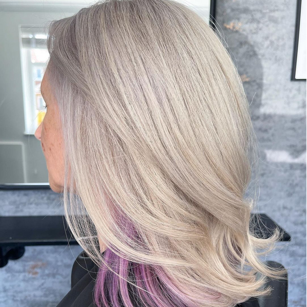 Side view of icy platinum blonde hair with a lavender underlayer peeking beneath, styled in soft layers