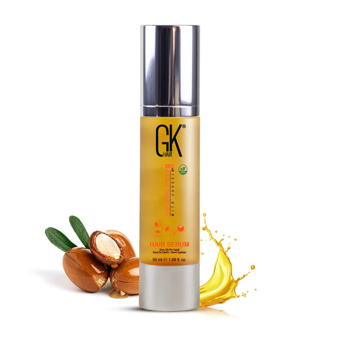 GK Hair Hair Serum, 50 ml / 1.69 fl. oz. silver-capped pump bottle, argan nuts and a splash of golden oil beside it