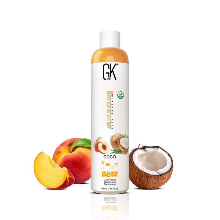 GK Hair The Best Coco Juvexin Treatment 300 ml white bottle with amber-tinted shoulder, flanked by peach and half a coconut