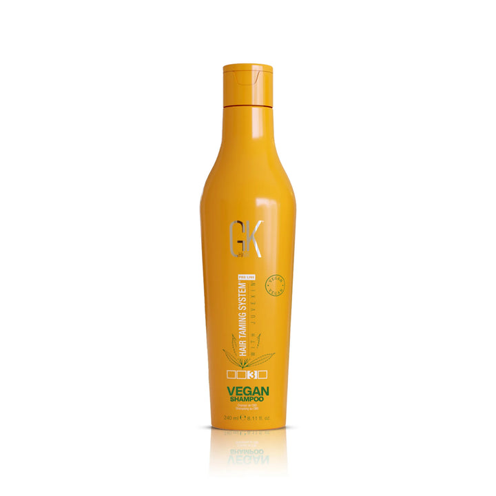 GK Hair Vegan Shampoo 240 ml golden-orange bottle with a flip cap, front view with reflection on white