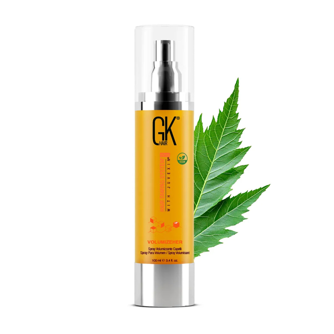 GK Hair VolumizeHer volumizing spray, 100 ml gold pump bottle with clear cap, large green serrated leaf angled behind it