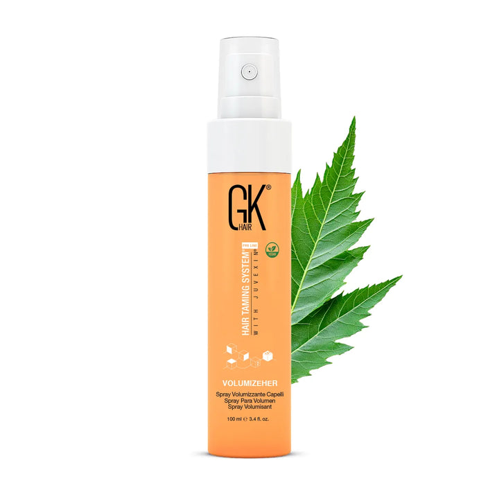GK Hair VolumizeHer 100 ml orange spray bottle with a white pump cap, a green leaf behind it on white