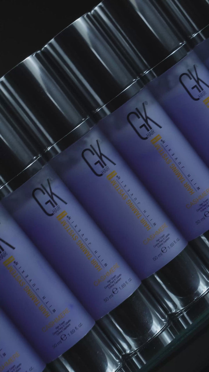 Rows of GK Hair Cashmere hair cream 50 ml lavender bottles with chrome pumps, then one standing alone against black