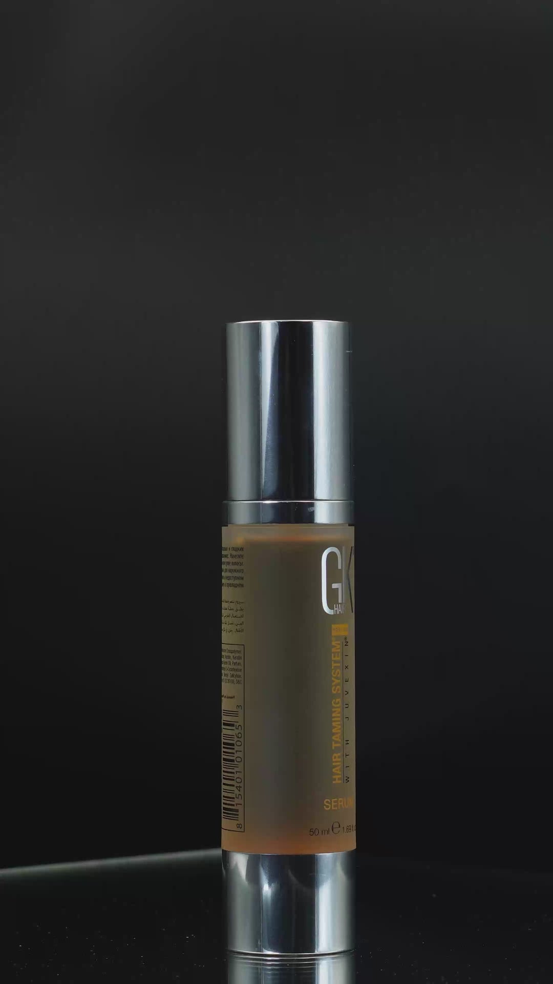 GK Hair Serum 50 ml in a frosted amber pump bottle on black, a gold drop falling onto the chrome pump