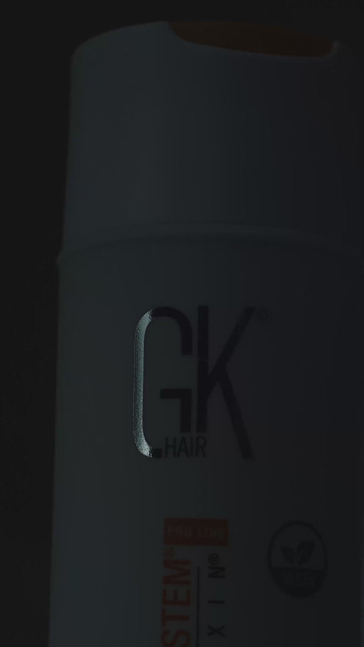 White GK Hair Taming System with Juvexin Pro Line bottle with an orange flip cap and vegan badge, beaded with water drops