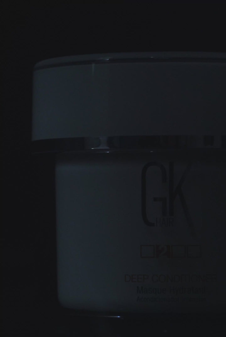 GK Hair Deep Conditioner masque jar in close crop on black, open lid revealing rich white cream and a metal spatula