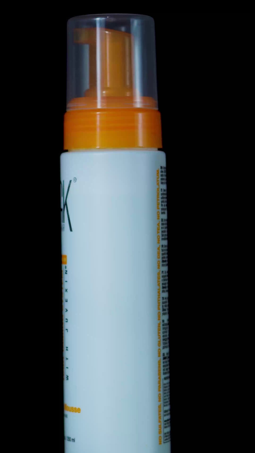 GK Hair Styling Mousse 8.5 fl. oz. / 250 ml can with an orange nozzle, beaded with droplets on black amid rising foam